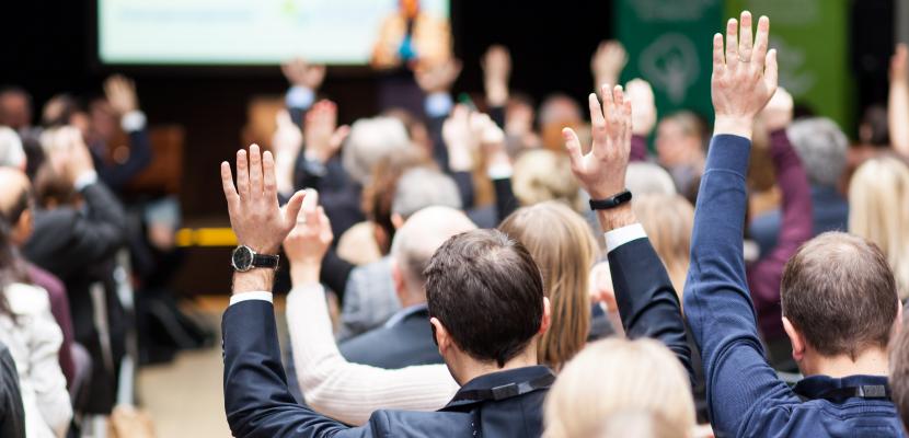 Participants of an event raising hands during a plenary