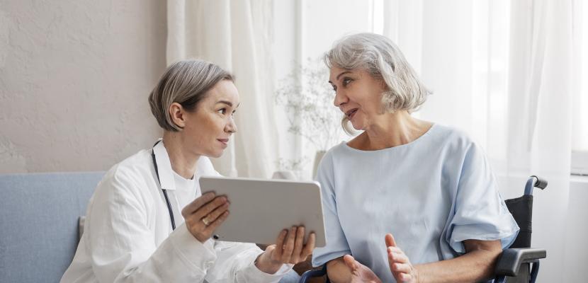 A doctor with a older patient using a connected tablet