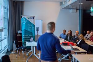 A speaker next to a Policy Learning Platform banner in a room 