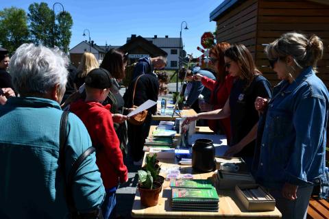 Many people looking books on the table outdoors at the open doors event.