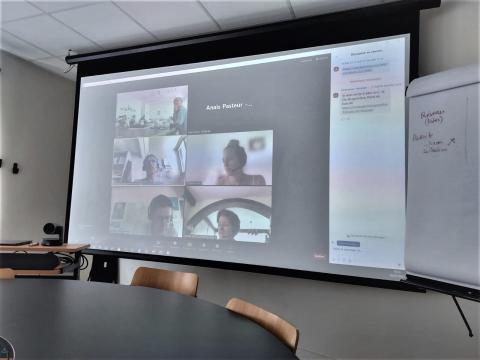 A big screen where is seen five video attendants in Teams meeting.