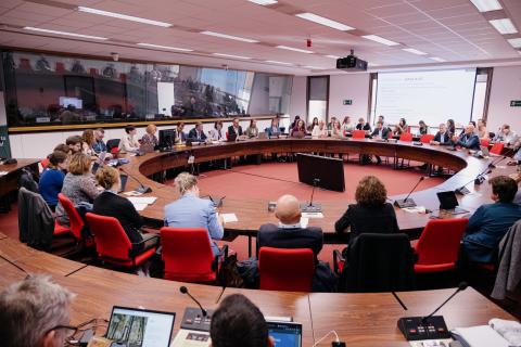 People around a round table, listening to the conference