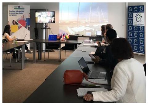 People in a meeting room looking at a screen with online meeting participants