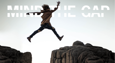 A person jumping over a gap between two big rocks.