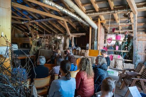 People sitting and watching a presentation under a wooden structure