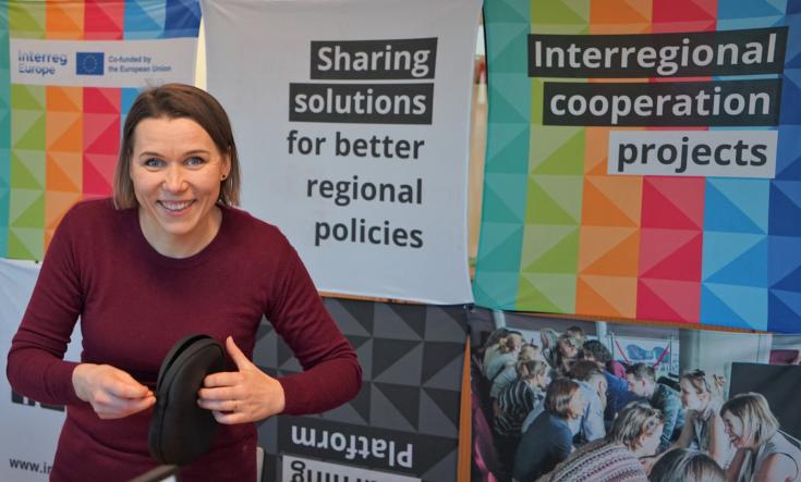 We organised a welcome webinar for new lead partners of Interreg Europe projects from the first call in 2021-2027 on 19 January person smiling and standing in front of a colourful Interreg Europe stand and holding headphones