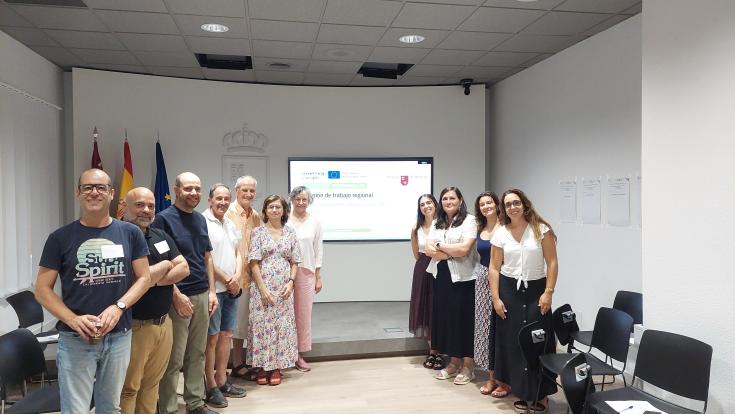 Group photo in a room. Adults watch the camera, behind them a powerpoint slide on a screen