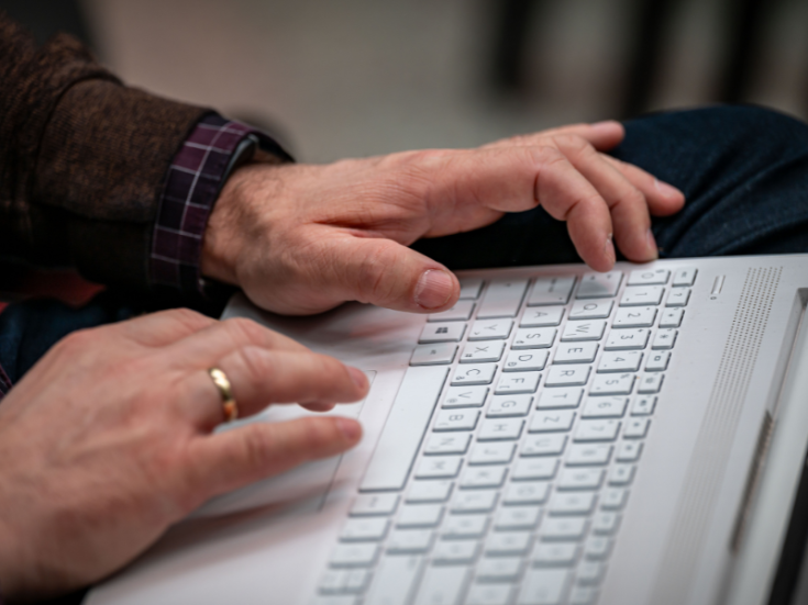 Close up of hands typing on white laptop keyboard.