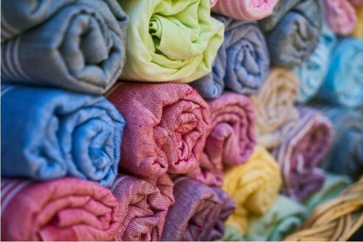 Stacked rolls of textiles, in several different colours