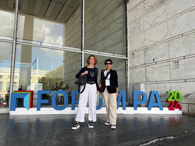 Two people standing in front of a sign for Forum PA 2024