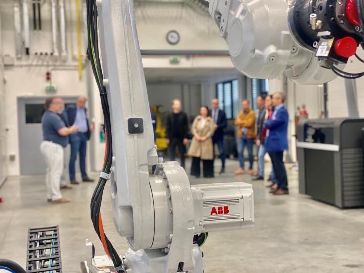 A group of people behind the arm of a robot A group of people behind the arm of a robot