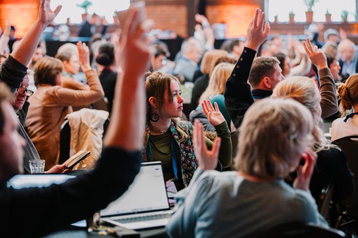 Group of people raise hands and look towards a stage at event