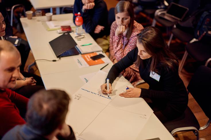 People sitting around table and writing on paper