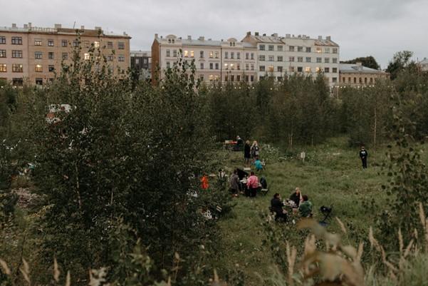 People sitting in a garden with buildings in the background