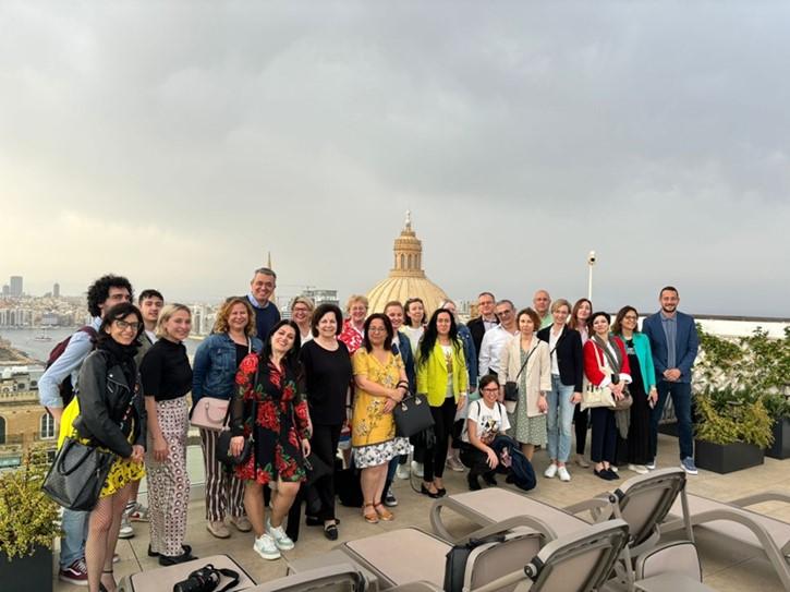 A group of colleagues stand in front of a view in Malta