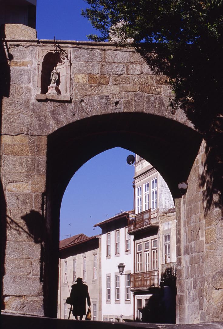 Eldery lady  passing under an old granite door with coat of arms