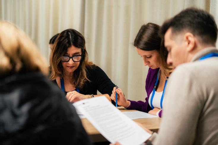 People sitting down around a table reading documents