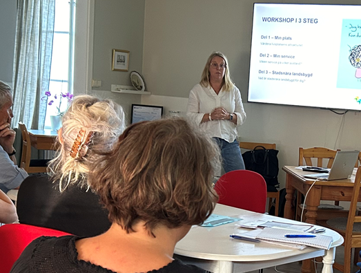 Person standing at top of room presenting to a group of people 