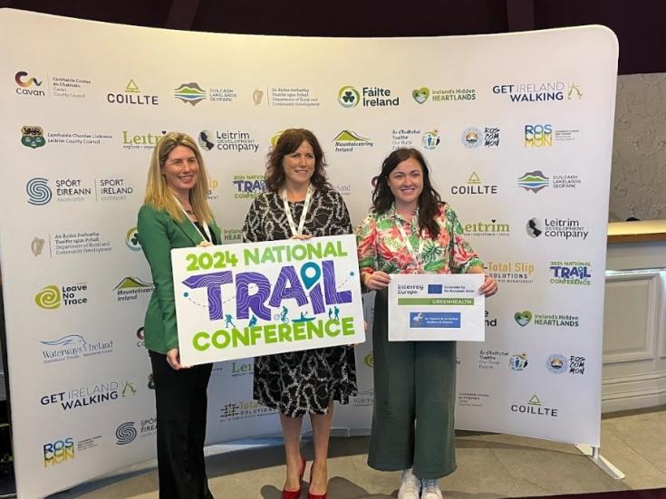 Three women hold banners about the 2024 Ireland Trails Conference. Eimear Dowd (centre) with Emma O'Hagan, conference organizer (right) and Teresa Roche chair of IFA Family & Social Affairs Committee (left)