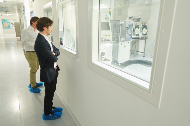 Two people looking at machines through a window Two people looking at machines through a window