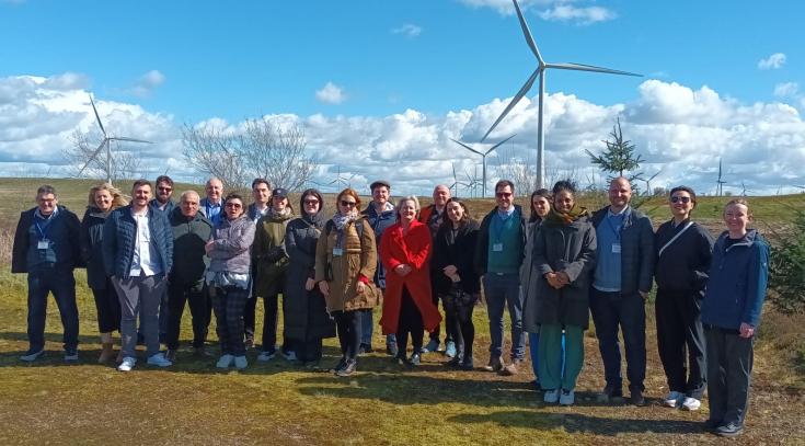 Members of the COMMIT consortium pose for photo in front of wind turbine park.