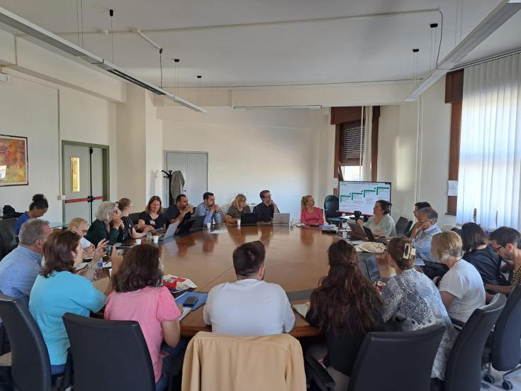 People sit in a room around a large table 