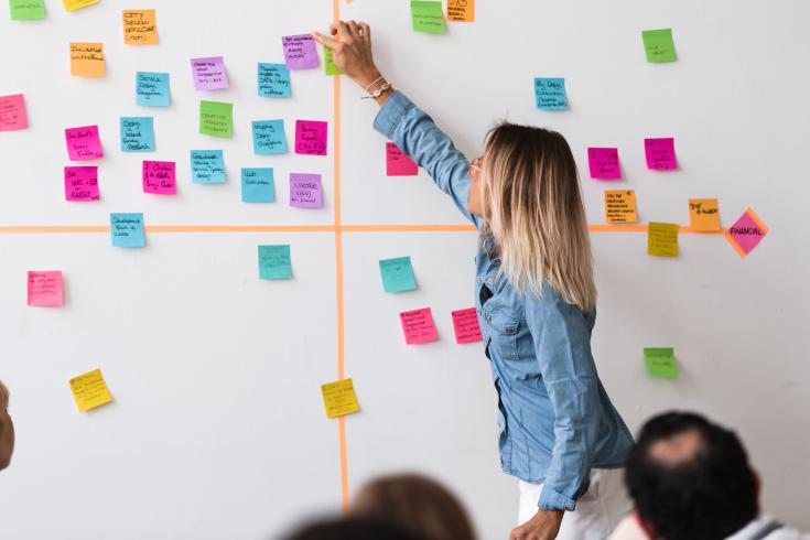 Woman sticking sticky note on wall