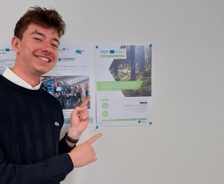 Young man pointing at the poster wall and smiling