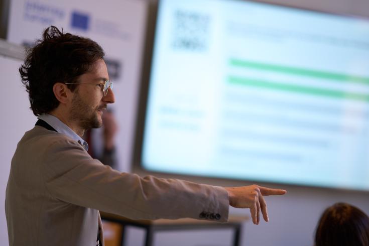Man in front of a screen pointing at someone Man in front of a screen pointing at someone