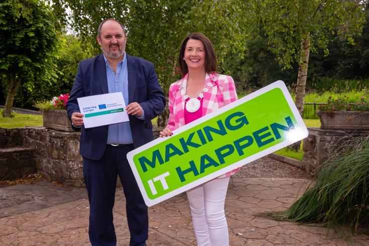 A man holds the InnoCom logo and a woman holds a sign that says Making it Happen