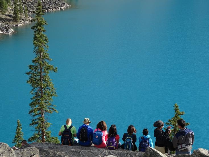 People sitting on rock edge facing a body of water