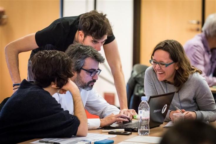 group of people working together and looking at a computer screen