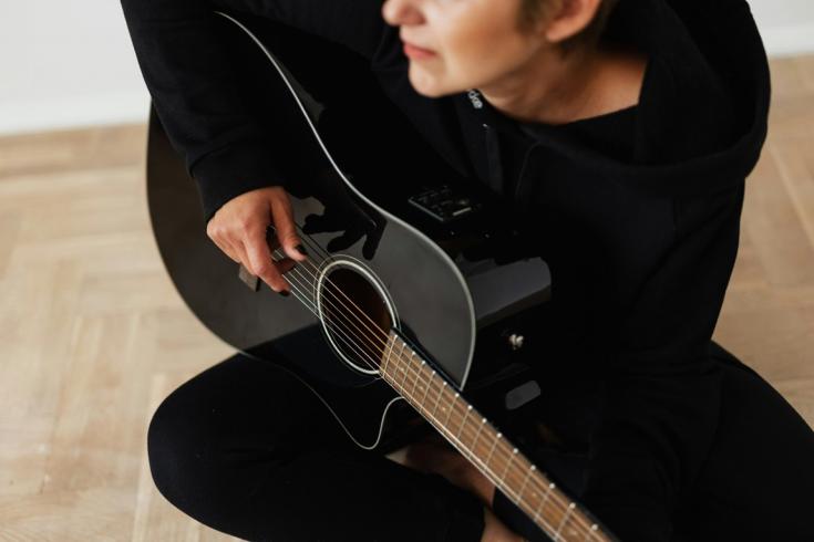 Person in black long sleeve playing accoustic guitar