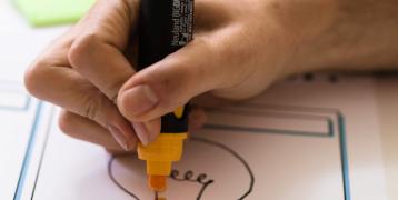 Hand drawing a light bulb with yellow pen Hand drawing a light bulb with yellow pen