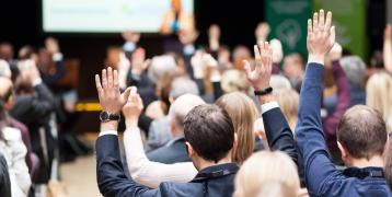 Participants of an event raising hands during a plenary