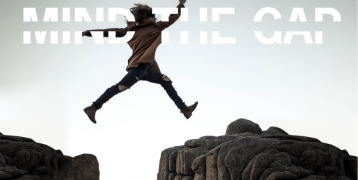 A person jumping over a gap between two big rocks.