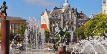 a city center with a fountain, buildings, statues