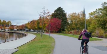Person biking down road next to river Person biking down road next to river