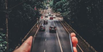 Person holding phone out of which a road appears Person holding phone out of which a road appears