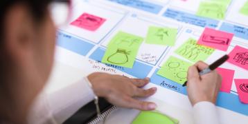 Person writing on sticky note Person writing on sticky note