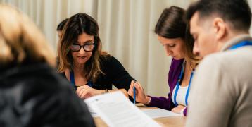 People sitting down around a table reading documents