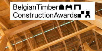 A wooden roof structure with visible beams and rafters, symbolizing timber construction. Overlaid is a logo reading "Belgian Timber Construction Awards" in black text, with geometric shapes representing buildings incorporated into the typography.