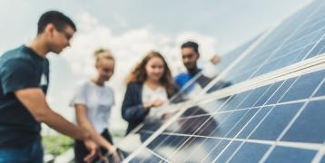 Group of people around a solar panel Group of people around a solar panel
