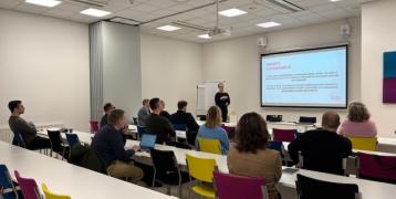 people gathered  in a room, looking at presentation