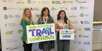 Three women hold banners about the 2024 Ireland Trails Conference. Eimear Dowd (centre) with Emma O'Hagan, conference organizer (right) and Teresa Roche chair of IFA Family & Social Affairs Committee (left)