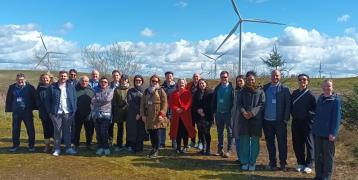 Members of the COMMIT consortium pose for photo in front of wind turbine park.