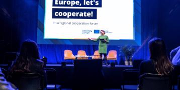 Europe, let's cooperate! interregional cooperation forum is the annual event of the Interreg Europe programme moderator on stage with a screen behind and audience in front