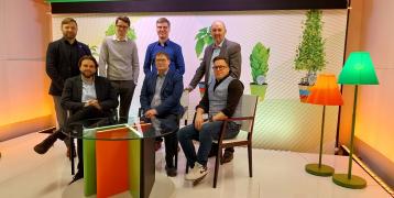 Seven people smiling for a picture, taken with colorful furniture 