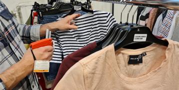 A person – only seen by hands – marking second-hand clothes on a hanger rack