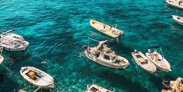 blue sea with boats and hills in the background